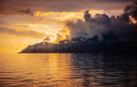 Sonnenuntergang am Meer. Berge der Amalfiküste in Wolken und Strahlen der untergehenden Sonne