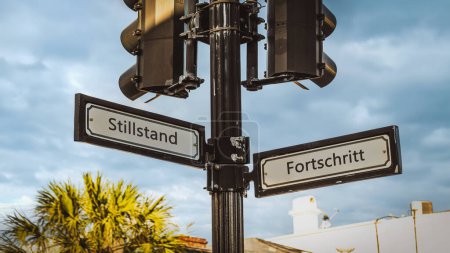 Téléchargez les photos : Une image avec un panneau pointant dans deux directions différentes en allemand. Une direction indique le progrès, l'autre indique la stagnation. - en image libre de droit