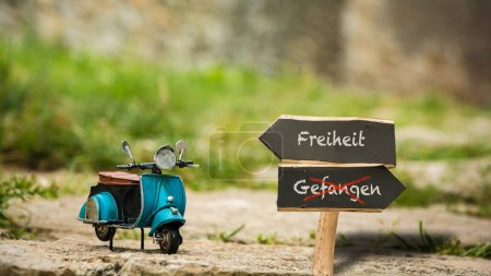 Photo for An image with a signpost pointing in two different directions in German. One direction points to freedom, the other points to captive. - Royalty Free Image