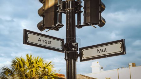 Téléchargez les photos : Une image avec un panneau pointant dans deux directions différentes en allemand. Une direction indique le courage, l'autre indique la peur. - en image libre de droit