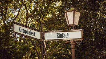 An image with a signpost pointing in two different directions in German. One direction points to Simple, the other points to Complicated.