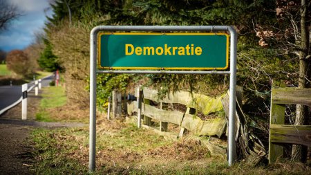 the picture shows a signpost and a sign that points in the direction of democracy in german.