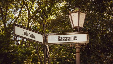 Foto de Una imagen con una señal apuntando en dos direcciones diferentes en alemán. Una dirección apunta al racismo, la otra apunta a la tolerancia. - Imagen libre de derechos