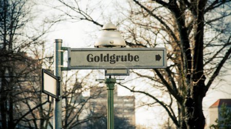 The picture shows a signpost and a sign that points in the direction of the gold mine in German.