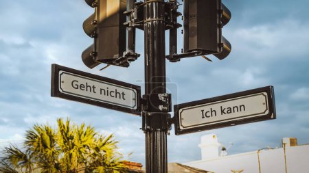 An image with a signpost pointing in two different directions in German. One direction points to I can, the other points to resignation.