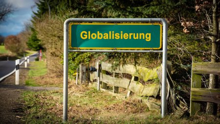 La imagen muestra una señal y un signo que apunta en la dirección de la globalización en alemán.