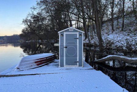 Téléchargez les photos : Lac en hiver. Bateau et maison d'équipement. Réflexions dans l'eau. Neige sur le rivage. - en image libre de droit