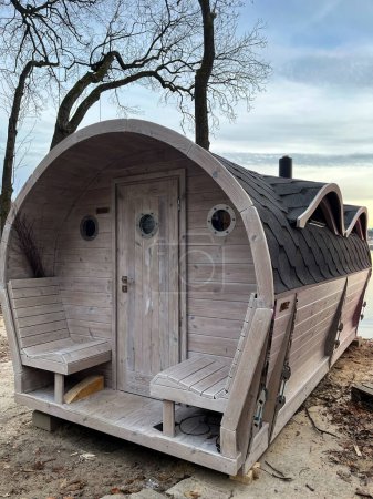 Outdoor sauna barrel made of wood. Mobile sauna in the form of a wooden barrel. Finnish SPA, relaxing holiday. Relaxation concepts. Popular rural mobile wooden sauna.