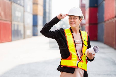 Retrato de una mujer trabajadora supervisora caucásica con sombrero duro trabajando con una tableta en un patio de contenedores. Gestión de empresas navieras y mercancías internacionales importación-exportación. Concepto de operación logística.