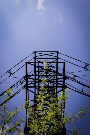 Metal support of a high-voltage power line with insulators on a sunny summer day against a blue sky