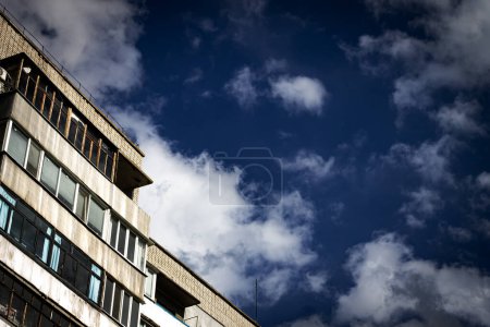 Die letzten Stockwerke eines mehrstöckigen Backsteingebäudes vor dem Hintergrund eines blauen Himmels mit weißen Wolken. Stadtskizzen, Steindschungel.