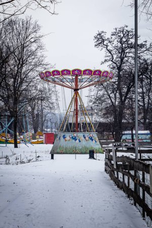Un manège lumineux dans un parc d'attractions en hiver par une journée nuageuse