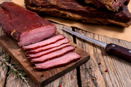 Téléchargez les photos : Planche à découper avec viande séchée, épices et couteau de cuisine sur une table en bois. Concentration sélective. - en image libre de droit