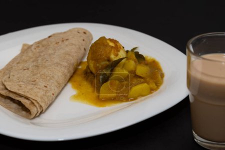 Foto de Desayuno al estilo indio. Chappathi y curry de huevo en fondo negro aislado - Imagen libre de derechos