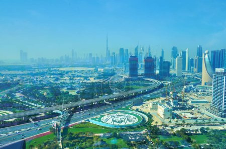 Téléchargez les photos : DUBAI, Émirats arabes unis - 6 MARS 2020 : Les gratte-ciel brumeux du centre-ville de Dubaï avec Burj Khalifa, dominant les toits, Sheikh Zayed Road et Sheikh Zayed photo d'herbe dans le parc Zabeel, le 6 mars à Dubaï - en image libre de droit