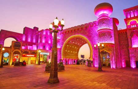 Foto de DUBAI, Emiratos Árabes Unidos - 6 de marzo de 2020: La Plaza de la Cultura de Global Village Dubai con vistas a la Puerta Cultural iluminada, decorada con arco de herradura, cortavientos y torres con cúpulas bulbosas, el 6 de marzo en Dubai - Imagen libre de derechos