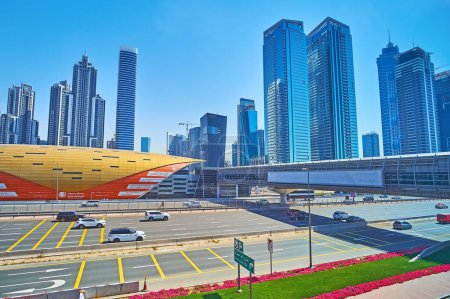 Téléchargez les photos : DUBAI, Émirats arabes unis - 2 MARS 2020 : La route animée Sheikh Zayed devant le pavillon de la station de métro Business Bay, le skywalk et les gratte-ciel en verre modernes, le 2 mars à Dubaï - en image libre de droit