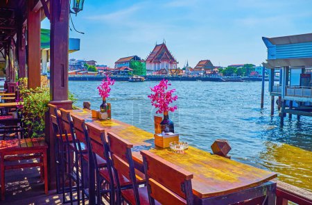 Foto de El café al aire libre junto al río con orquídeas en botellas en las mesas con vistas al Chao Phraya en Bangkok, Tailandia - Imagen libre de derechos