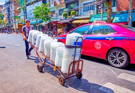 Photo for BANGKOK, THAILAND - APRIL 23, 2019: Young porter carying large packs of ice along the road at Pak Khlong Talat Flower Market, on April 23 in Bangkok, Thailand - Royalty Free Image