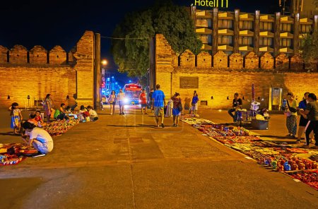 Téléchargez les photos : CHIANG MAI, THAÏLANDE - 3 MAI 2019 : Le petit marché à la porte Tha Pae et les ruines du mur de la forteresse en brique avec des créneaux dans des lumières tamisées, le 3 mai à Chiang Mai - en image libre de droit
