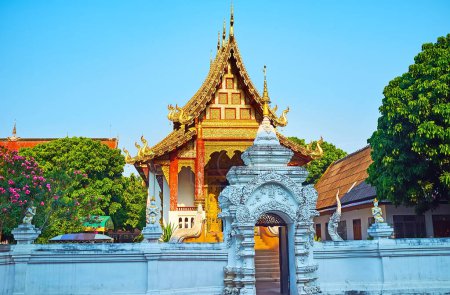 Photo for The carved white gate of Wat Chang Taem temple, decorated with reliefs, golden hti umbrella, devata sculptures on the fence, Chiang Mai, Thailand - Royalty Free Image