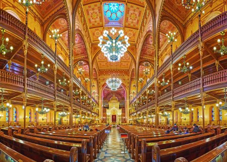 Téléchargez les photos : BUDAPEST, HONGRIE - 22 février 2022 : Panorama de la salle de prière de la synagogue historique Dohany Street avec plafond orné, arche de Torah sculptée et meubles en bois, le 22 février à Budapest - en image libre de droit