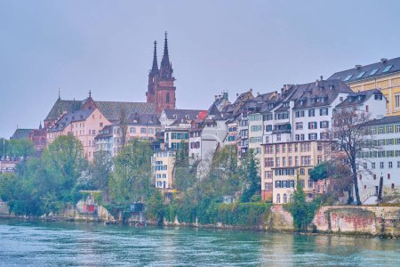 Téléchargez les photos : The spires of Basel Minster above the roofs of residential townhouses on bank of Rhine river, Switzerland - en image libre de droit