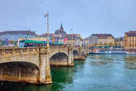 Téléchargez les photos : BASEL, SWITZERLAND - APRIL 1, 2022: The view on Mittlere Brucke across Rhine river in rainy day, on April 1 in Basel, Switzerland - en image libre de droit
