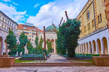 Foto de The small court and cemetery of Dohany Street Synagogue with old trees, covered with green ivy, Budapest, Hungary - Imagen libre de derechos