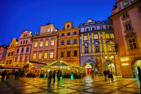 Téléchargez les photos : PRAGUE, CZECHIA - MARCH 11, 2022: The line of colorful medieval townhouses on Old Town Square with restaurants on ground floor in bright illumination, on March 11 in Prague, Czechia - en image libre de droit