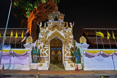 Photo for The richly decorated gate of Wat Chedi Luang with sculptures of Devata deities, Naga serpents and Yaksha guardians against the dark evening sky, Chiang Mai, Thailand - Royalty Free Image