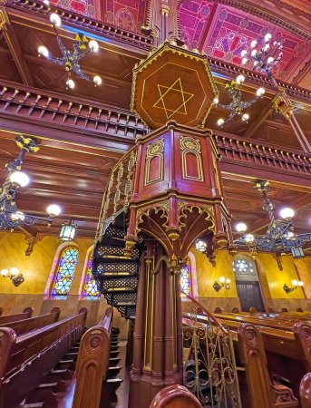 Téléchargez les photos : BUDAPEST, HUNGARY - FEB 22, 2022: Dohany Street Synagogue prayer hall with rich wooden decorations and carved pulpit with gilt patterns, on Feb 22 in Budapest - en image libre de droit