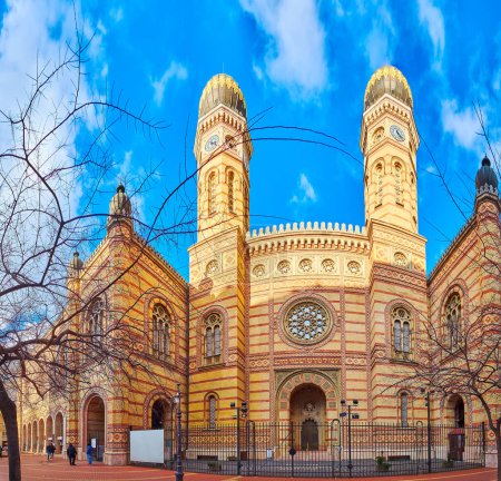Téléchargez les photos : La pittoresque façade mauresque de la synagogue Dohany Street avec des dômes bulbeux au sommet des tours d'horloge, des rosiers, des sculptures et des motifs de briques colorées, Budapest, Hongrie - en image libre de droit