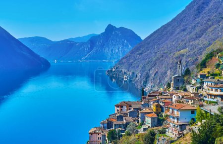 Foto de Albogasio Superiore settlement of Valsolda on the Alpine slope against the mirror-like Lake Lugano, mountain slopes and Monte San Salvatore, Italy - Imagen libre de derechos