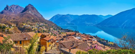 Panorama of Castello from the top of the hill with a view on Lake Lugano, tile roofs and rocky Lugano Prealps with peaks of Monte dei Pizzoni and Monte Bronzone, Valsolda, Italy