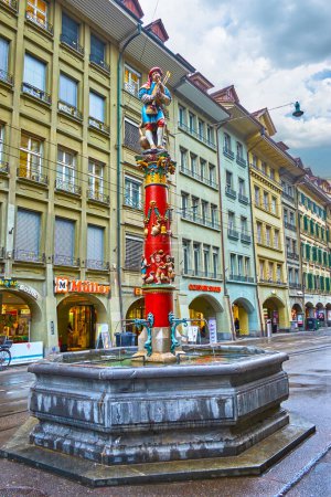 Foto de BERN, SUIZA - 31 DE MARZO DE 2022: Colorida fuente Pfeiferbrunnen con escultura de Minstrel situada en la calle Spitalgasse, el 31 de marzo en Berna, Suiza - Imagen libre de derechos
