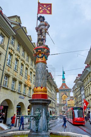 Foto de BERN, SUIZA - 31 de marzo de 2022: Fuente medieval de Schutzenbrunnen en medio de la calle Marktgasse, el 31 de marzo en Berna, Suiza - Imagen libre de derechos