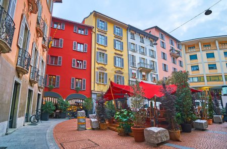 Foto de Histórica Piazza Cioccaro con casas de colores y comedor al aire libre, rodeado de plantas verdes en macetas, Lugano, Suiza - Imagen libre de derechos