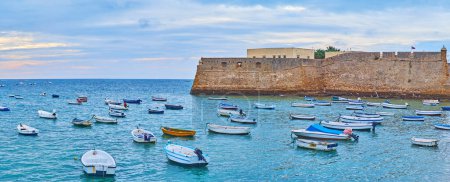 Téléchargez les photos : Panorama du front de mer avec petits bateaux de pêche et dériveurs devant le château de Santa Catalina, Cadix, Espagne - en image libre de droit