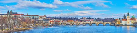 Téléchargez les photos : Paysage urbain panoramique avec une rivière Vltava ondulée d'un bleu profond, un pont Charles voûté médiéval et la cathédrale Saint-Vitus, dominant l'horizon de la ville, Prague, République tchèque - en image libre de droit