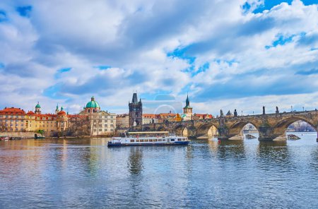 Foto de El barco turístico en el río Moldava contra el puente de Carlos y la vivienda de la Ciudad Vieja, Praga, Chequia - Imagen libre de derechos