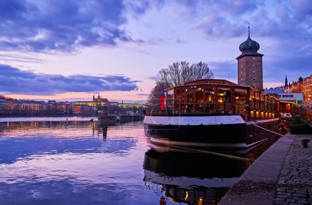 Téléchargez les photos : Le ciel violet sur le château d'eau médiéval Sitkov derrière le bateau-restaurant sur la rivière Vltava, Prague, Tchéquie - en image libre de droit