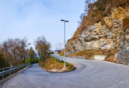 Photo for The mountain serpentine road, lined with forest and steep rock, leading to the Monte Bre top, Lugano, Switzerland - Royalty Free Image