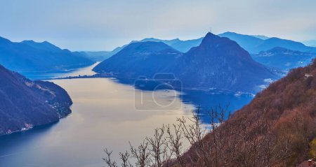 Téléchargez les photos : Profitez de la vue sur le Monte San Salvatore, le lac de Lugano et la chaussée de Melide recouverte de brume légère, Tessin, Suisse - en image libre de droit