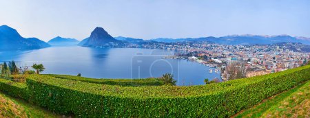 Photo for Panorama of Lake Lugano from San Michele Park, observing Lugano embankment and roofs, Monte San Salvatore and Lugano Prealps, Ticino, Switzerland - Royalty Free Image