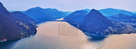 Téléchargez les photos : Vue aérienne de Lugano, lac azur Lugano, silhouette floue du Monte San Salvatore et de la Chaussée Melide depuis le sommet du Monte Bre, Tessin, Suisse - en image libre de droit
