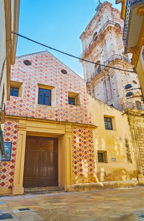 La façade et le haut clocher de l'église historique San Juan de l'étroite rue Calderon de la Barca à Malaga, Espagne