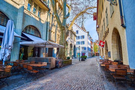 Téléchargez les photos : ZURICH, SUISSE - 3 AVRIL 2022 : Shady In Gassen street avec tables de patio de restaurants, le 3 avril à Zurich, Suisse - en image libre de droit