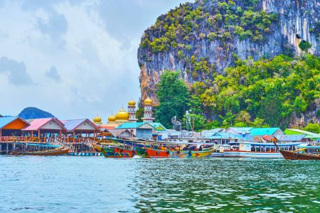 Foto de El viaje en barco a lo largo de la orilla de Ko Panyi (Koh Panyee) pueblo flotante con vistas a los astilleros, casas de zancos, muelles de madera y cúpulas de oro de la mezquita local, Ao Phang Nga, Tailandia - Imagen libre de derechos