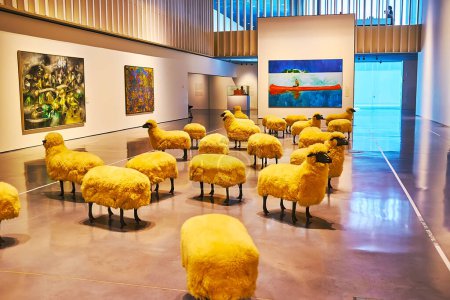Photo for MALAGA, SPAIN - SEPT 28, 2019: The flock of sheep by Francois-Xavier Lalanne in a hall of Centre Pompidoy Museum with paintings on the walls, around the sculptural group - Royalty Free Image